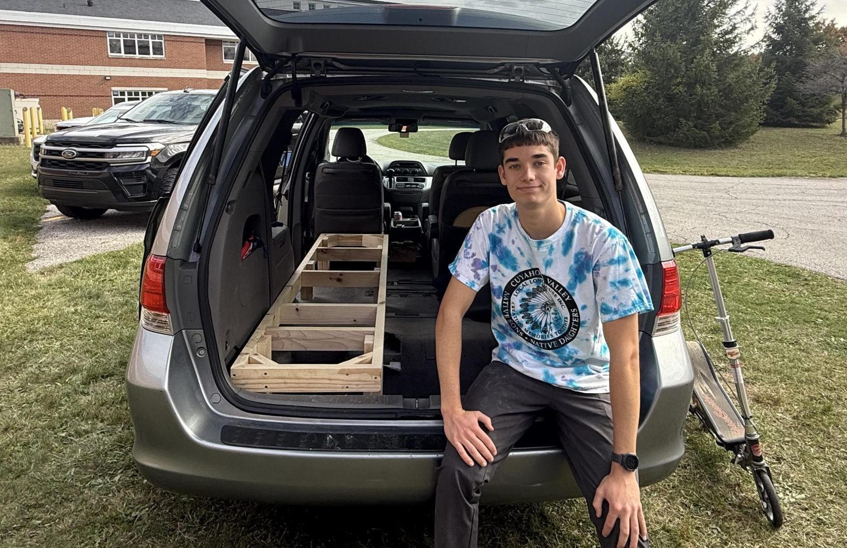 Senior Tate McGovern sits in his 2010 Honda Odyssey. Driver-side bedframe visible beside him.