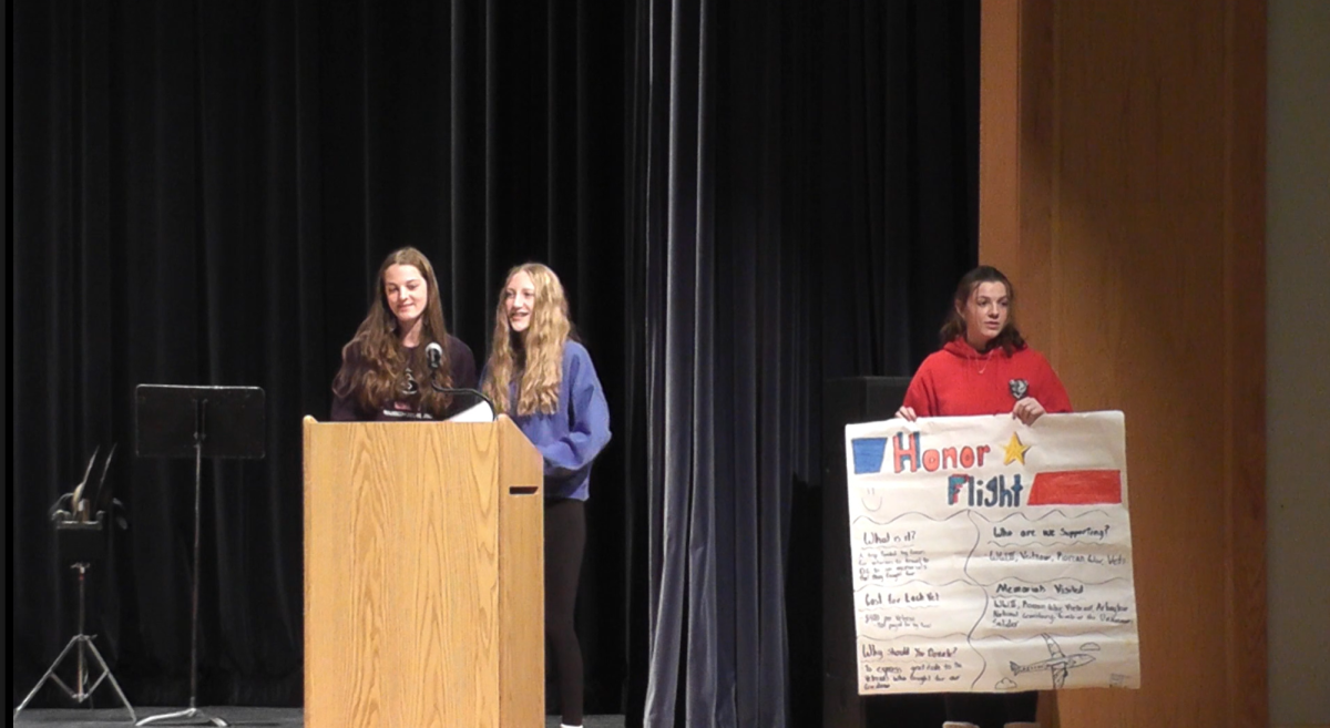 Eighth graders Cameron Bauman and Scarlett Lewis talk about Honor Flight Cleveland, an organization that flies veterans to Washington, D.C. Rachel Mehosky holds a poster.