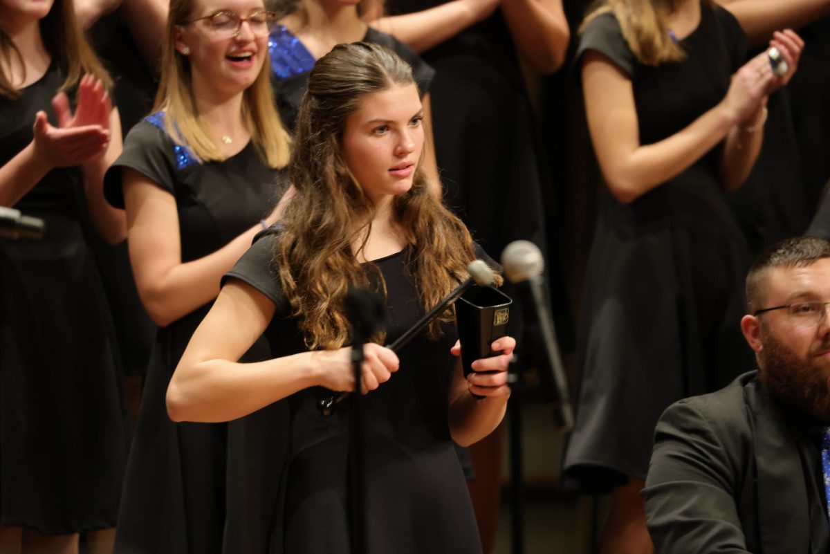 Freshman Leah Creel playing the cowbell for the IHS Vocal Ensemble.