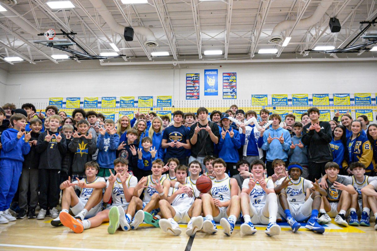 The Independence student section and the Varsity Basketball team posing with the Heights and Independence rival trophy.