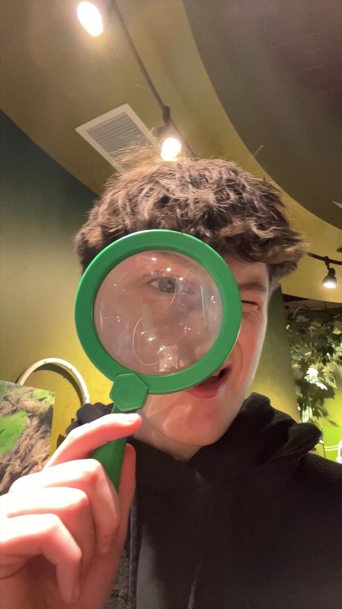 Ryan Suhy humorously looks through a magnifying glass