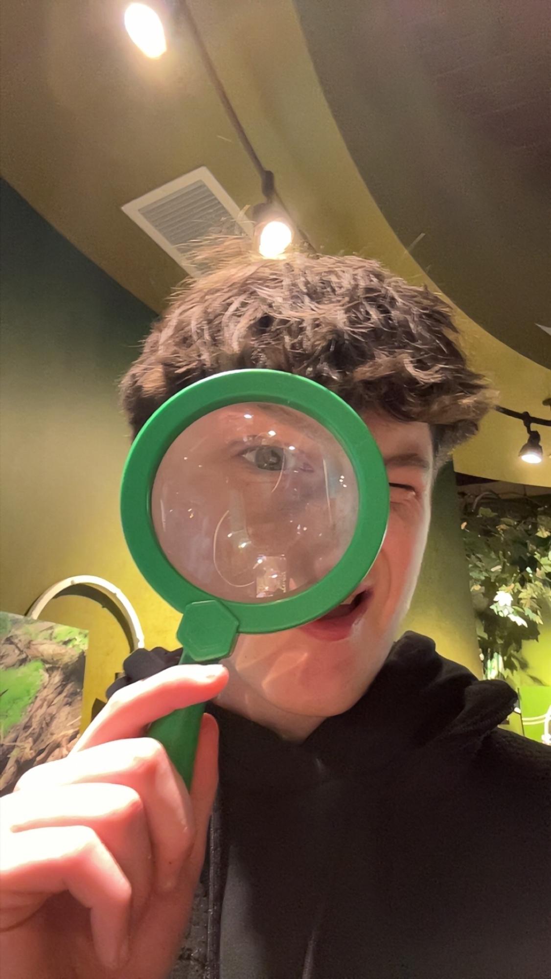 Ryan Suhy humorously looks through a magnifying glass